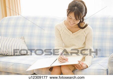 Stock Photo - Young woman writing on notebook. Fotosearch