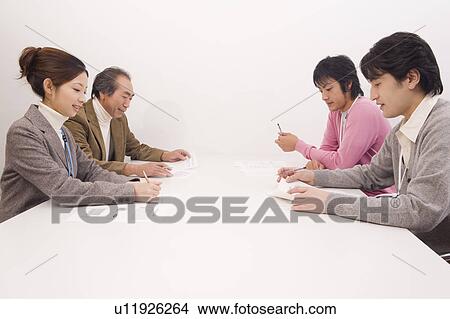 Picture - Four people discussing in meeting room. Fotosearch