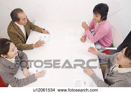 Picture - Four people discussing in meeting room. Fotosearch