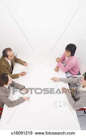 Stock Photo - Four people discussing in meeting room. Fotosearch