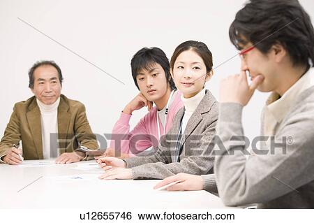 Stock Photograph - Four people discussing in meeting room. Fotosearch