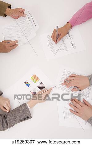 Stock Photo - Hands of four people on desk. Fotosearch