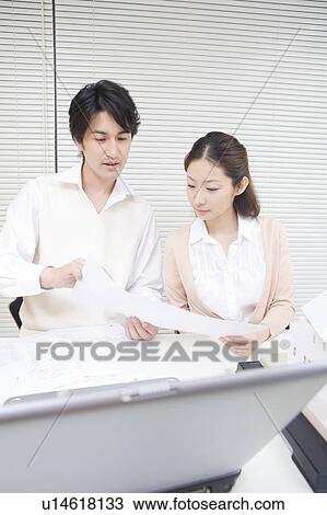 Mid adult man and young woman looking at document View Large Photo Image Stock Image - Mid adult man and young woman looking at document. Fotosearch