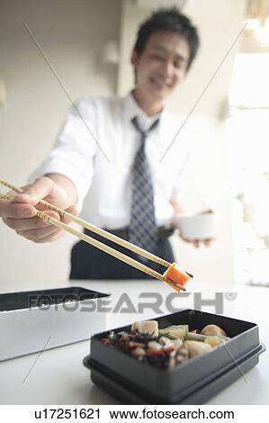 Stock Image - Businessman cooking in lunch box. Fotosearch