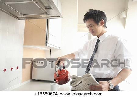 Businessman holding kettle in kitchen View Large Photo Image Picture - Businessman holding kettle in kitchen. Fotosearch