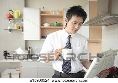 Businessman reading newspaper in kitchen View Large Photo Image Picture - Businessman reading newspaper in kitchen. Fotosearch