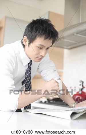 Businessman reading newspaper in kitchen View Large Photo Image Stock Image - Businessman reading newspaper in kitchen. Fotosearch