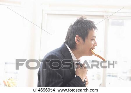 Picture - Mid adult man dressing and eating. Fotosearch