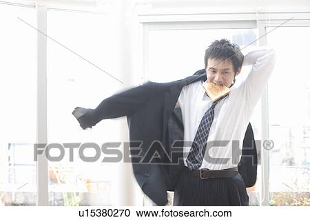 Stock Image - Mid adult man dressing and eating. Fotosearch