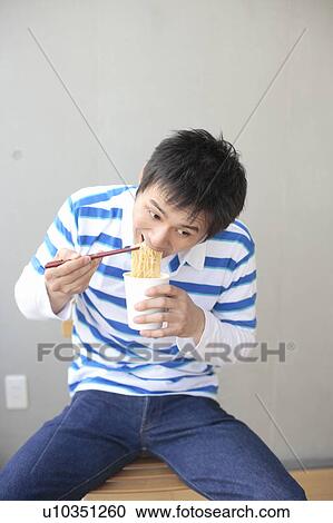 Mid adult man eating instant noodle View Large Photo Image Stock Image - Mid adult man eating instant noodle. Fotosearch
