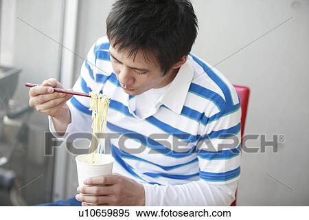 Mid adult man eating instant noodle View Large Photo Image Stock Photography - Mid adult man eating instant noodle. Fotosearch
