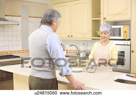 Stock Image - Senior couple cooking. Fotosearch