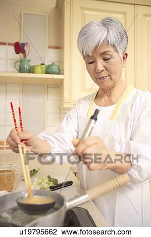 Stock Image - Senior woman cooking. Fotosearch