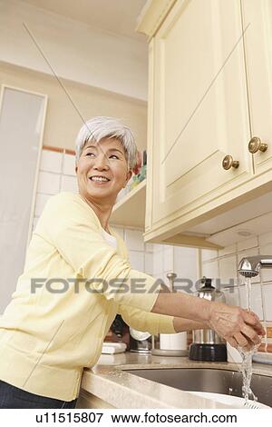 Stock Photo - Senior woman standing in kitchen. Fotosearch