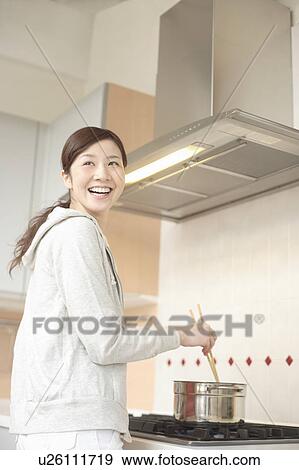 Young woman cooking in kitchen View Large Photo Image Stock Photo - Young woman cooking in kitchen. Fotosearch