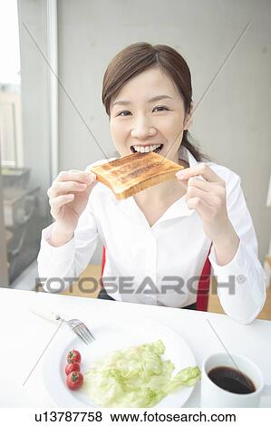Stock Photo - Young woman eating breakfast. Fotosearch
