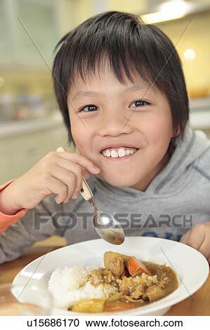 Stock Image - Boy eating curry and rice. Fotosearch