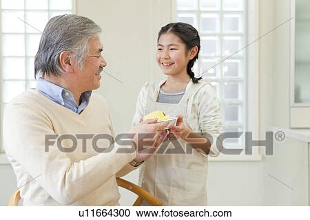 Stock Image - Grandson serving apple to grandfather. Fotosearch