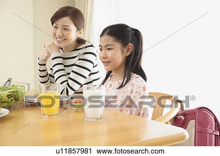Stock Image - Mother and daughter having breakfast. Fotosearch