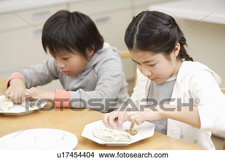 Picture - Two children making pot-sticker. Fotosearch