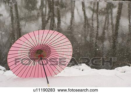 Stock Image - Paper umbrella on snowfield. Fotosearch