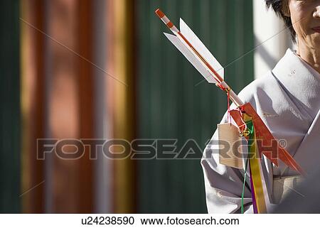 Stock Image - Woman in kimono holding decorative arrow. Fotosearch