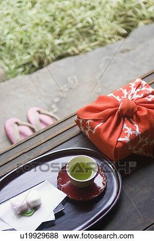 Stock Photo - Wrapped gift and tea cup on veranda. Fotosearch