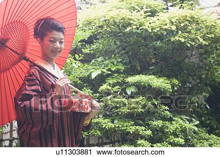 Young woman in kimono holding paper umbrella View Large Photo Image Stock Image - Young woman in kimono holding paper umbrella. Fotosearch