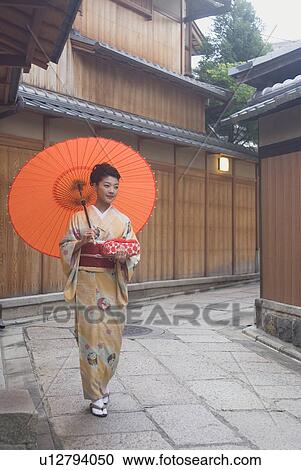 Stock Image - Young woman in kimono holding paper umbrella. Fotosearch