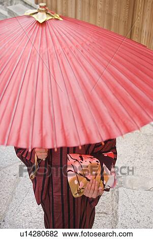 Stock Image - Young woman in kimono holding paper umbrella. Fotosearch
