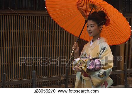 Stock Image - Young woman in kimono holding paper umbrella. Fotosearch
