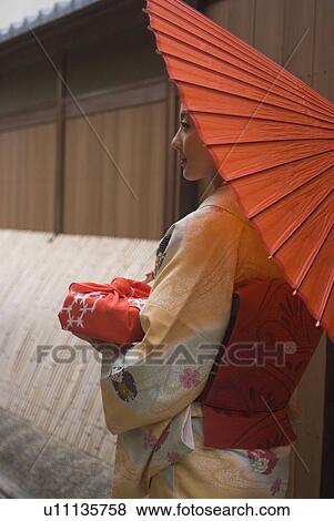 Young woman in kimono holding paper umbrella View Large Photo Image Stock Photo - Young woman in kimono holding paper umbrella. Fotosearch