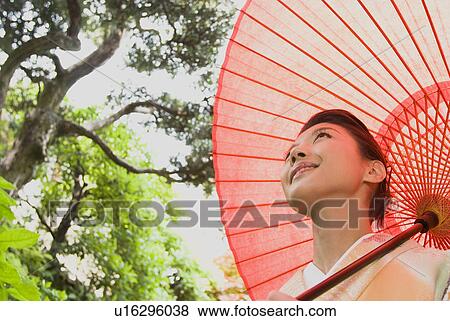 Young woman in kimono holding paper umbrella View Large Photo Image Stock Photo - Young woman in kimono holding paper umbrella. Fotosearch