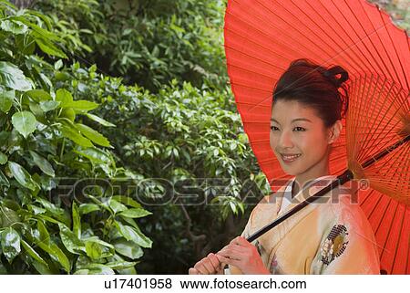 Stock Photo - Young woman in kimono holding paper umbrella. Fotosearch