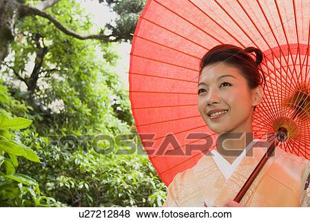 Stock Photo - Young woman in kimono holding paper umbrella. Fotosearch