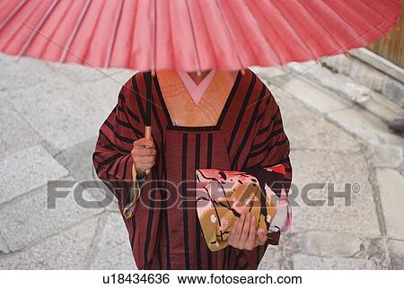 Stock Photograph - Young woman in kimono holding paper umbrella. Fotosearch