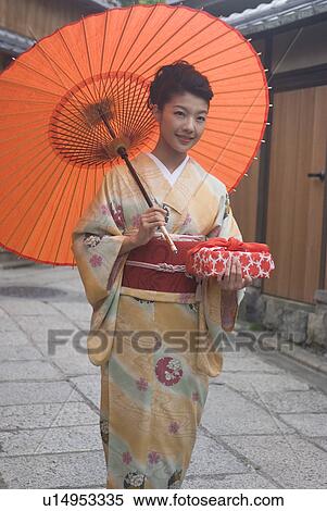 Stock Photography - Young woman in kimono holding paper umbrella. Fotosearch