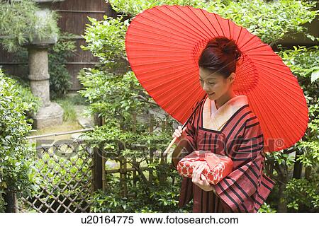 Young woman in kimono holding paper umbrella View Large Photo Image Stock Photography - Young woman in kimono holding paper umbrella. Fotosearch