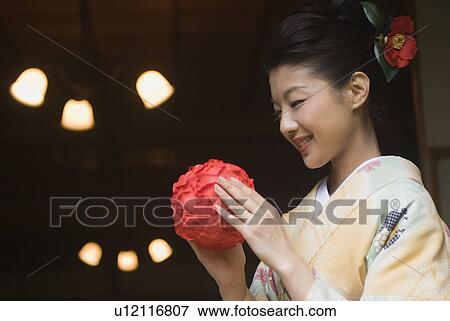 Stock Photo - Young woman in kimono holding temari ball. Fotosearch