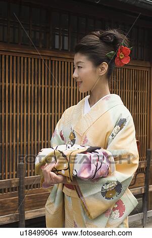 Picture - Young woman in kimono holding wrapped gift. Fotosearch
