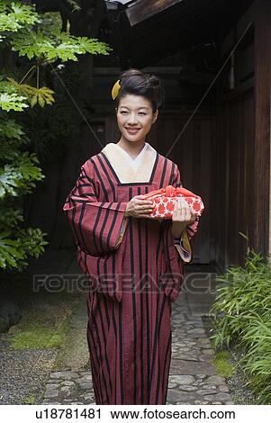 Young woman in kimono holding wrapped gift View Large Photo Image Stock Image - Young woman in kimono holding wrapped gift. Fotosearch