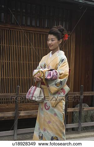 Stock Photo - Young woman in kimono holding wrapped gift. Fotosearch