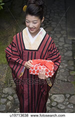 Young woman in kimono holding wrapped gift View Large Photo Image Stock Photo - Young woman in kimono holding wrapped gift. Fotosearch