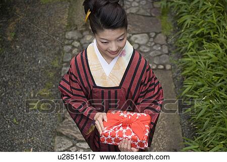Young woman in kimono holding wrapped gift View Large Photo Image Stock Photo - Young woman in kimono holding wrapped gift. Fotosearch