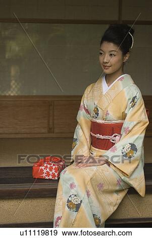 Stock Photo - Young woman in kimono sitting at veranda. Fotosearch