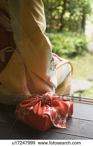 Stock Photo - Young woman in kimono sitting at veranda. Fotosearch