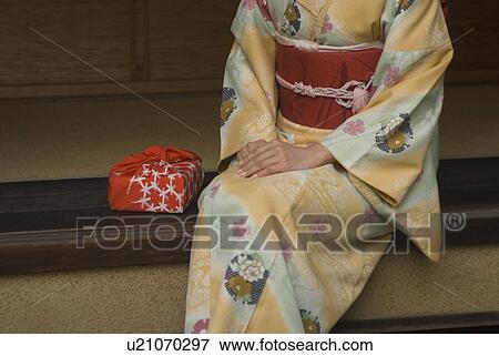 Stock Photo - Young woman in kimono sitting at veranda. Fotosearch