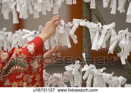 Stock Photo - Young woman tying fortune paper. Fotosearch