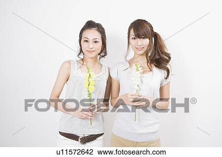 Two young women holding flowers View Large Photo Image Stock Image - Two young women holding flowers. Fotosearch