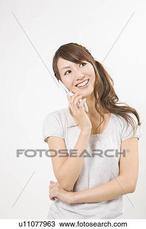 Stock Image - Young woman holding mobile phone. Fotosearch